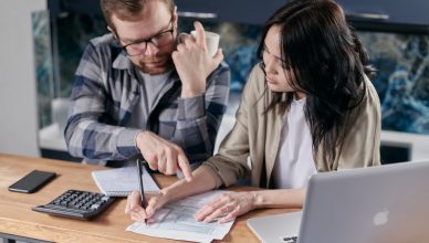 A couple analyzing financial documents with calculator and laptop on a table. — 4 Robust Forex Trading Indicators for the Ret