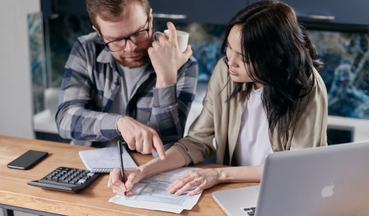 A couple analyzing financial documents with calculator and laptop on a table. — 4 Robust Forex Trading Indicators for the Ret
