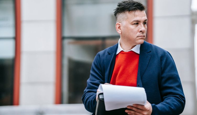 A serious man holding papers, dressed professionally in an urban environment. — 4 Things Every Landlord Should Know