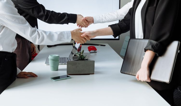 Professionals sealing a deal with a handshake across a conference table during a business meeting. — 5 Things Every Investor