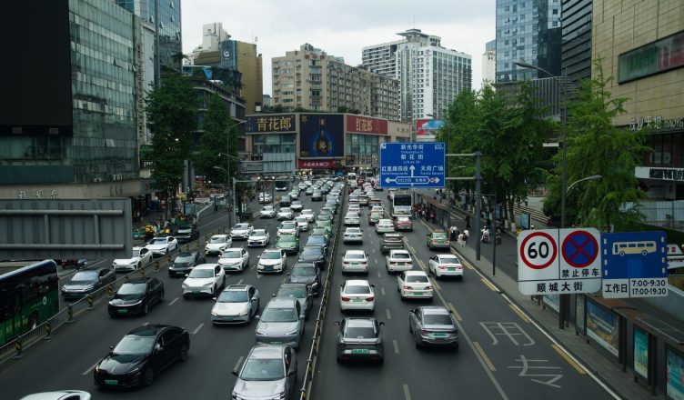 Heavy traffic on a busy Shanghai street lined with skyscrapers and billboards during the day. — A proper bag is required to c