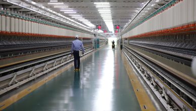 A man walks through a well-lit hallway in a modern industrial textile plant in India. — All you need to know about Fume Extra