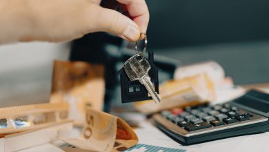 Close-up of a hand holding keys over euros and calculator, symbolizing real estate purchase. — All You Need to Know About Nat