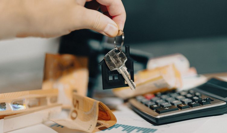 Close-up of a hand holding keys over euros and calculator, symbolizing real estate purchase. — All You Need to Know About Nat