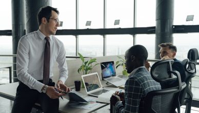 Three men engaged in a business meeting in a modern office setting with laptops and documents. — An overview of Faculty devel
