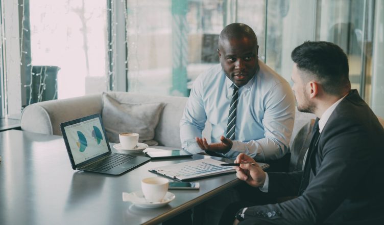 Two business professionals engaged in discussion over laptops and documents. — Avoid this common mistake to increase your con