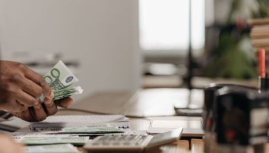 Close-up of hands counting euro bills at an office desk with a calculator. — Being a successful share trader