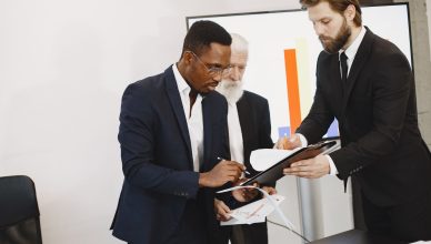 Three businessmen engaged in document signing in a modern office setting. — Benefits Of Having Cpa Services In Portland
