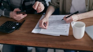 Couple managing finances at home with a calculator, smartphone, and documents. — Benefits of Hiring Mortgage Loan Advisory Br