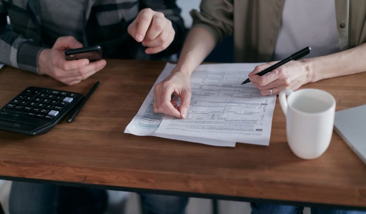 Couple managing finances at home with a calculator, smartphone, and documents. — Benefits of Hiring Mortgage Loan Advisory Br