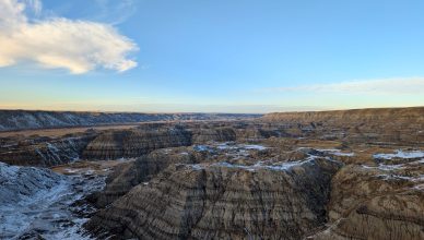 Wide view of the rugged Badlands landscape with snow patches under a clear blue sky. — Buy Quality Chairs for Your Office Use