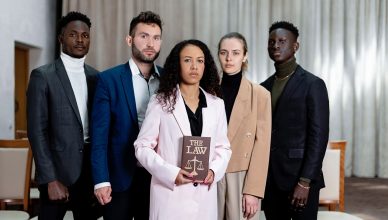 A diverse group of five lawyers posing confidently with a law book in an office setting. — Common Term Insurance Myths Debunk