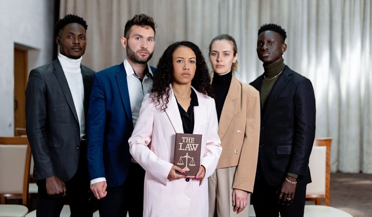 A diverse group of five lawyers posing confidently with a law book in an office setting. — Common Term Insurance Myths Debunk