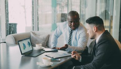 Two businessmen discussing data at a cafe while enjoying coffee. — Enjoy Cannabis Cigarettes for a Smooth Experience