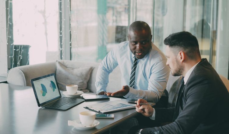 Two businessmen discussing data at a cafe while enjoying coffee. — Enjoy Cannabis Cigarettes for a Smooth Experience