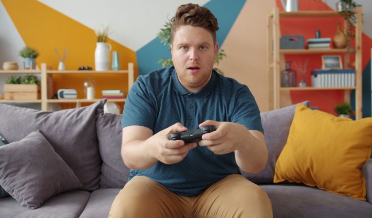 A young man intensely playing video games in a modern living room setting. — Exploring the W88 Live Lottery: Fast-Paced Fun a