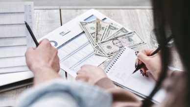 Two people working on financial documents and dollar bills for budgeting. — Finest Options for the Smartest Debt Recovery Now