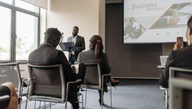 A business professional delivering a presentation in a conference room with diverse attendees. — Frequently Asked Questions R