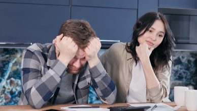 A couple looking worried while reviewing financial documents at a kitchen table. — Home Loan Interest Rate