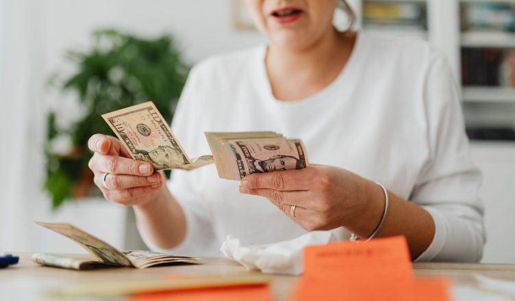 A woman sits indoors counting cash at her office desk, focusing on finances. — How Can Corporate Loans Help You To Establish