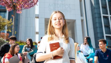 Happy university students socializing on campus, with a focus on a smiling young woman holding a book. — How can you achieve