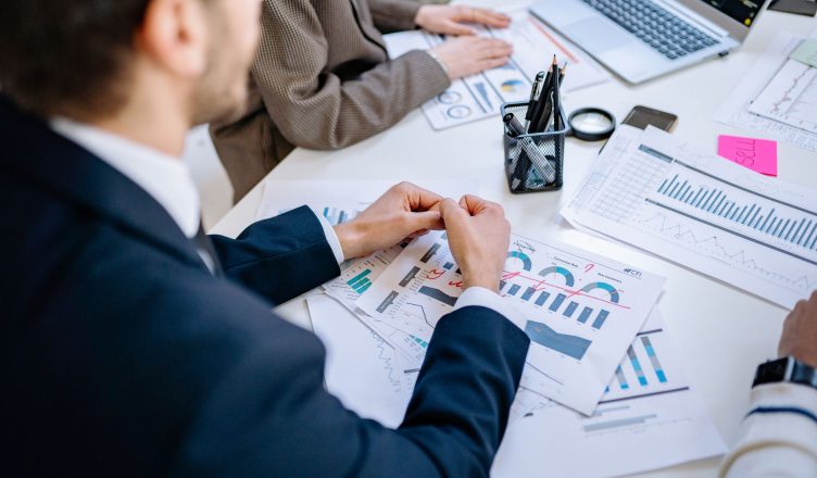Business team analyzing financial graphs at a meeting table, fostering collaboration in an office environment. — How can you