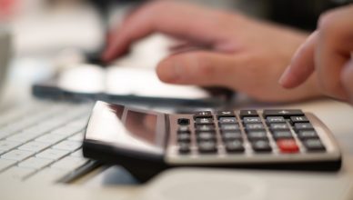 Close-up of hands using a calculator and keyboard in a financial setting, indoors. — How Easy It Is To Get Loans Without Cred
