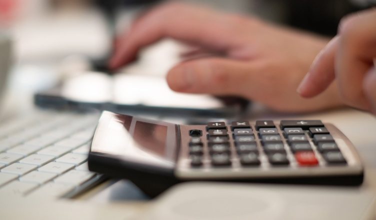 Close-up of hands using a calculator and keyboard in a financial setting, indoors. — How Easy It Is To Get Loans Without Cred