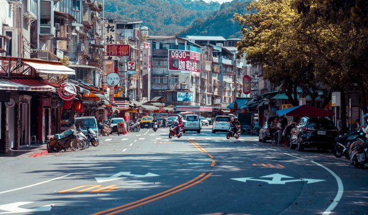 Vibrant urban street scene with shops, vehicles, and mountains in an Asian city. — How Google Ranks Its Pages