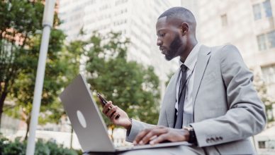 Businessman in a suit using a laptop and smartphone in an urban setting, blending technology with business. — How to Choose t