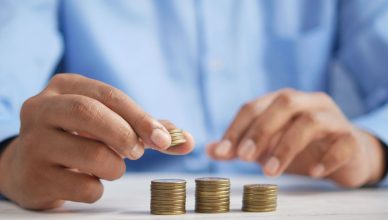 Close-up of hands stacking gold coins, symbolizing financial growth and savings. — How to Track the Performance of ULIPs?