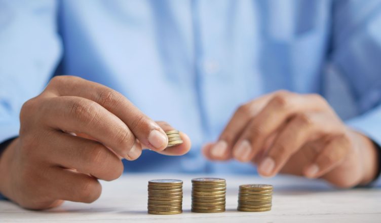 Close-up of hands stacking gold coins, symbolizing financial growth and savings. — How to Track the Performance of ULIPs?