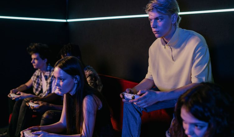 Group of focused teenagers playing video games indoors, immersed in teamwork and concentration. — HWID Spoofing: The Key to B