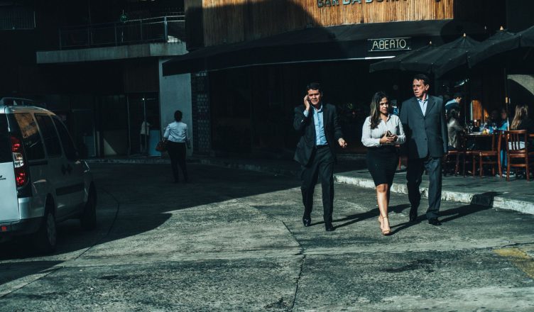 Three business professionals walk along a city street outside a cafe. — In what ways does the Online Teacher Training Course