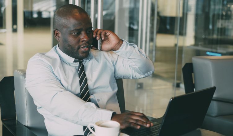 Professional man multitasking, talking on the phone while using a laptop in an office. — Is it safe to use an open-source rap