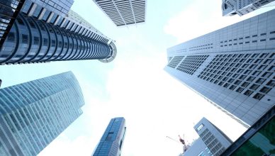 A striking upward view of various skyscrapers in an urban setting against a clear sky. — KINDS OF INFLATION AND ITS EFFECTS