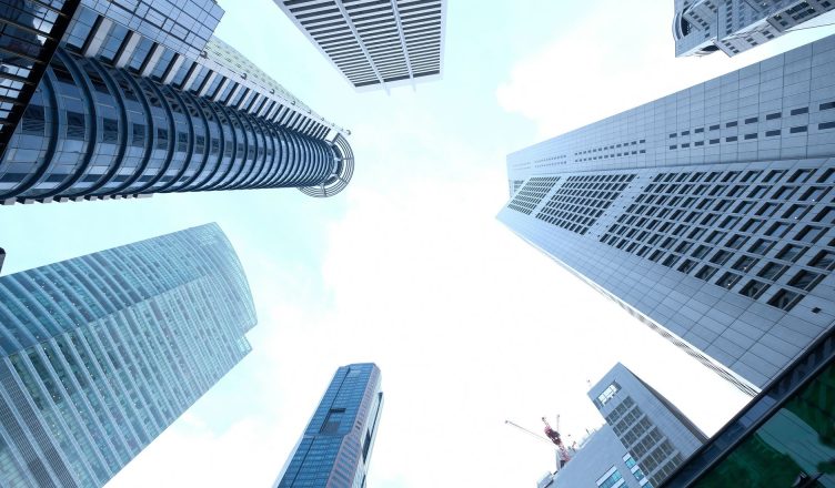 A striking upward view of various skyscrapers in an urban setting against a clear sky. — KINDS OF INFLATION AND ITS EFFECTS