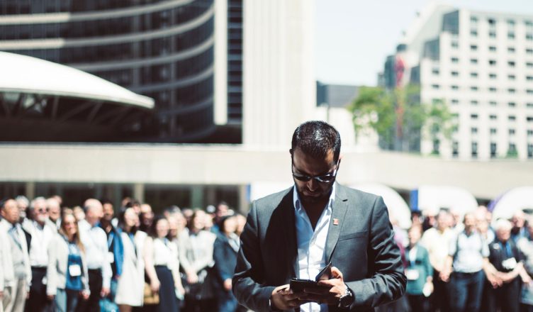 Focused businessman using tablet in a bustling crowd in Toronto's busy urban setting. — Mistakes You Should Avoid While Selec