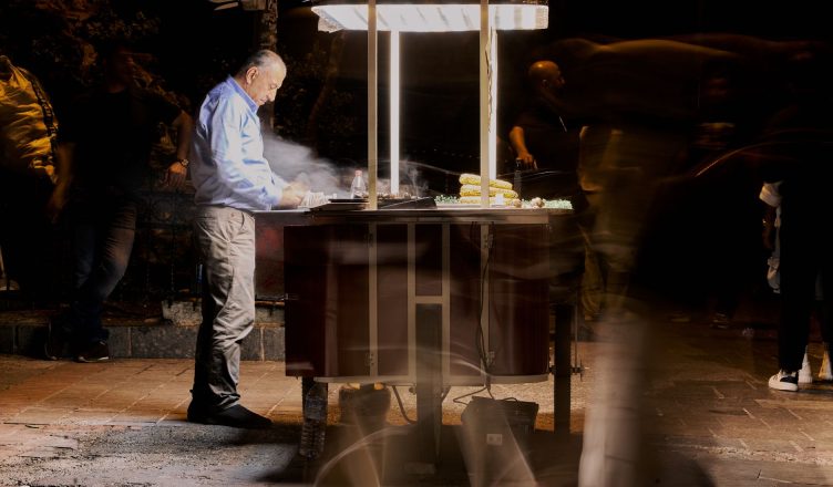 Street vendor cooking food at night with blurred people passing by. — Nangs Delivery Brisbane: Setting the Standard for Urban