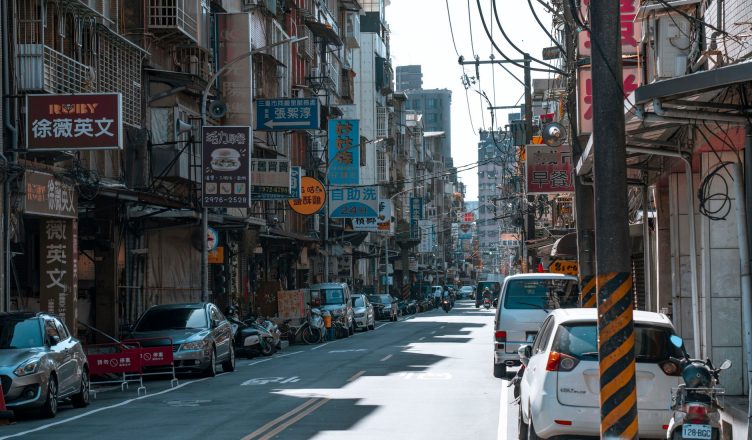 A busy street lined with cars and various colorful business signs on a sunny day. — NYSE GME Trading And All The Information