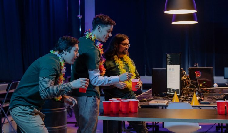 Group of male colleagues enjoying a fun beer pong game during an office party night. — PC Game Hacks-what are Benefits