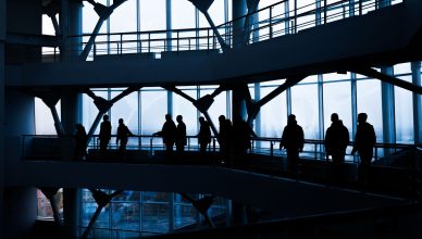Silhouettes of people walking in a modern architectural building with large windows. — REASONS BEHIND THE IMPORTANCE OF SOUND