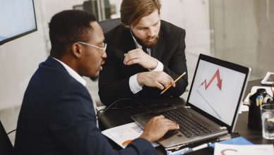 Two business professionals discuss marketing data on a laptop in a modern office. — Reasons to Choose Quality Equipment for Y