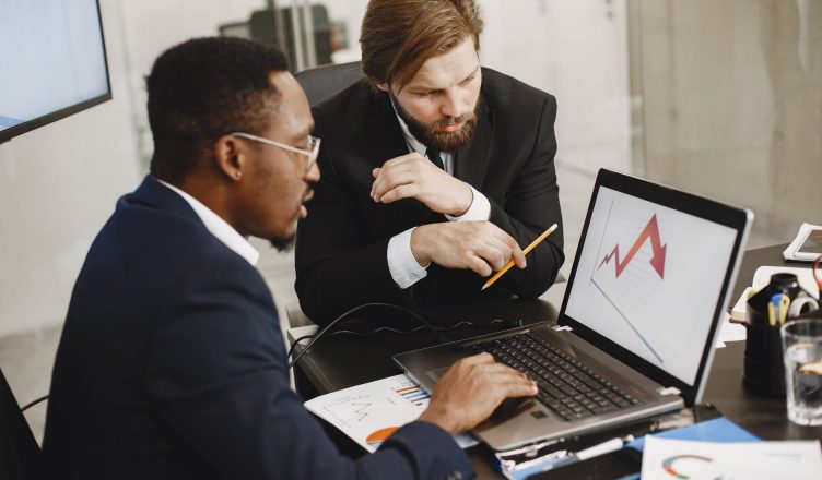 Two business professionals discuss marketing data on a laptop in a modern office. — Reasons to Choose Quality Equipment for Y
