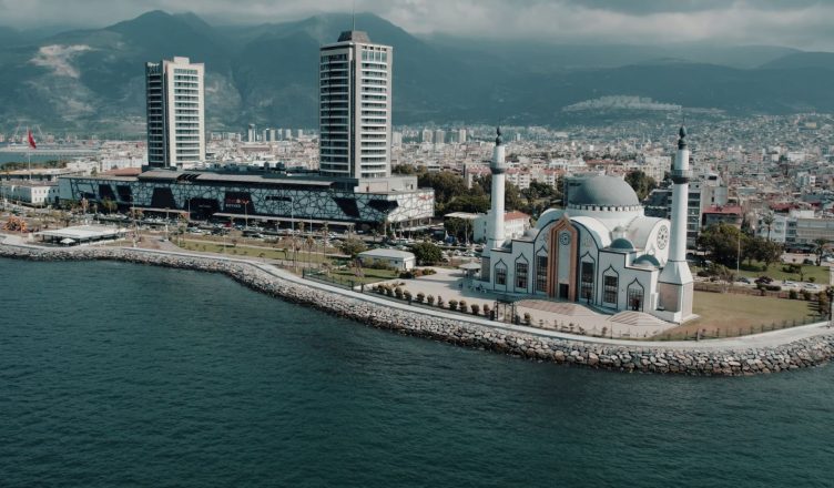 Aerial photograph showcasing İskenderun's mosque and cityscape against the mountainous backdrop on a sunny day. — Reasons why