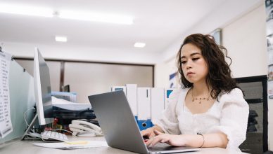 Professional woman working on a laptop in a modern office environment. — SEO: How a Search Engine Optimization Company Can He