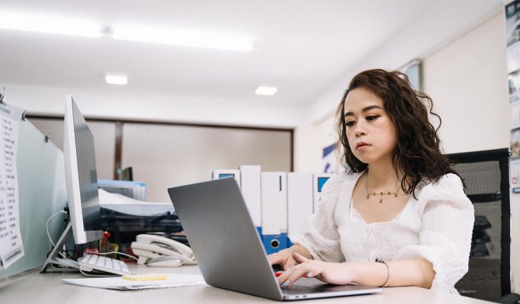 Professional woman working on a laptop in a modern office environment. — SEO: How a Search Engine Optimization Company Can He