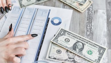Close-up of hands analyzing financial document with US dollar bills on table. — Effective trading strategies