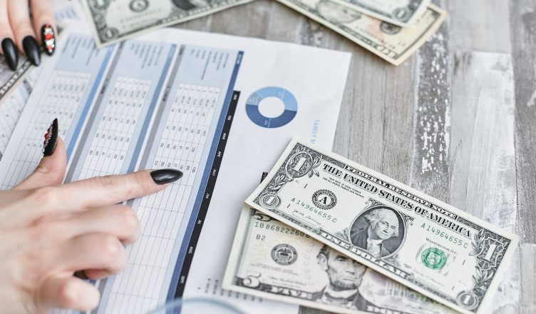 Close-up of hands analyzing financial document with US dollar bills on table. — Effective trading strategies
