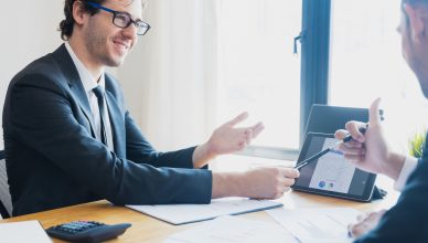 Two businessmen in formal attire discussing a business report in an office setting with a tablet. — SUCCESSFUL FOREX TRADING